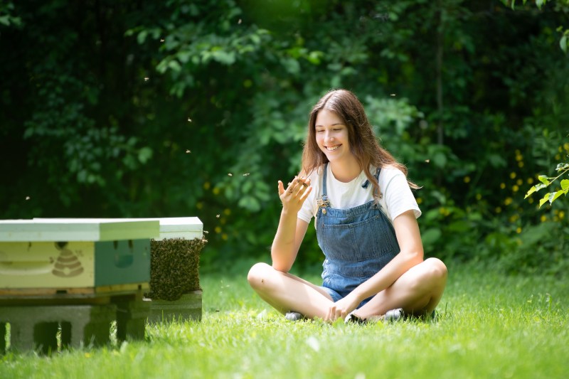 katie sitting by a hive and holding bees